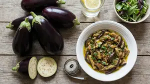 Melanzane fresche e melanzane cotte in una ciotola con olio ed erbe su tavolo di legno
